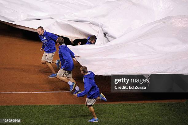 Members of the groundcrew bring a tarp out on the field as one falls down in the eighth inning in game six of the 2015 MLB American League...