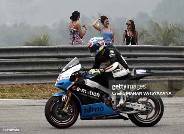 Women watch as Octo IodaRacing Team's Sammarinese rider Alex De Angelis powers his bike during the third practice session of the MotoGP Malaysian...