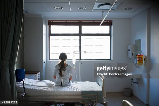 patient sitting on hospital bed waiting - bed foto e immagini stock