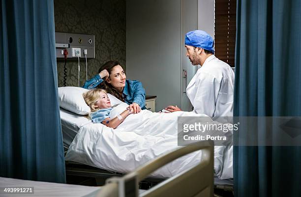 mother and daughter listening to an doctor - chirurgenkappe stock-fotos und bilder
