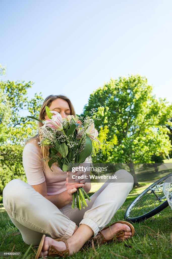 Young woman sitting with bouquet in park