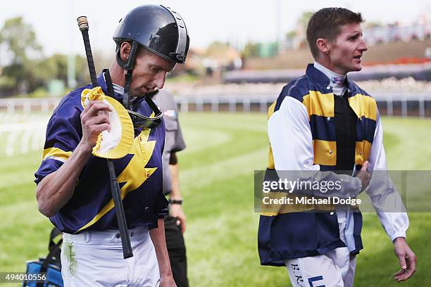 Jockey Nash Rawiller walks off with his brother Brad Rawiller after he fell off his horse Big Memory after the finish line during Cox Plate Day at...
