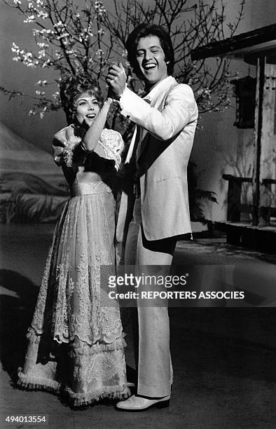 La chanteuse Mireille Mathieu en robe longue et le chanteur Joe Dassin en costume blanc chantent et dansent pour une émission de télévison, circa...