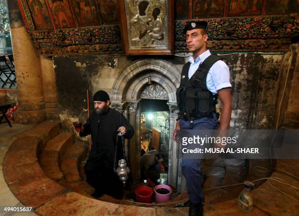 Palestinian policeman stands guard as a priest emerges from the Grotto, at the Church of the Nativity, believed to be the birthplace of Jesus Christ,...