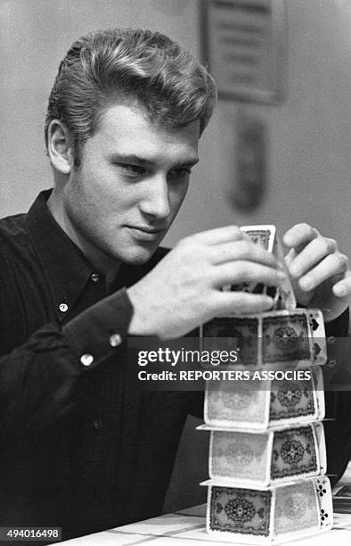 Johnny Hallyday fait un chateau de cartes en France, circa 1960.
