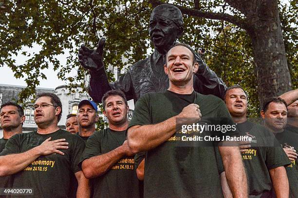 Captain Francois Pienaar and the 1995 South African Rugby World Cup winning squad lead fans in a rendition of their national anthem by a statue of...