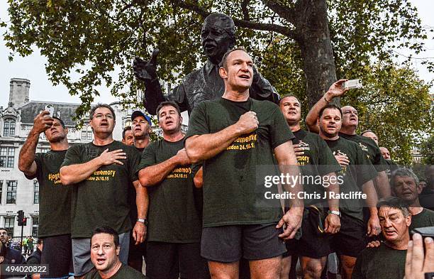 Captain Francois Pienaar and the 1995 South African Rugby World Cup winning squad lead fans in a rendition of their national anthem by a statue of...