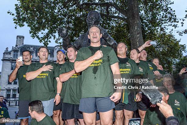 Captain Francois Pienaar and the 1995 South African Rugby World Cup winning squad lead fans in a rendition of their national anthem by a statue of...