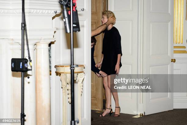 Assistants make final adjustments to Charlize Theron's hair and dress before she poses for photographers during a photo call for her latest film "A...