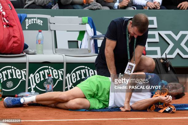 France's Michael Llodra gets medical assistance by a physiotherapist during his French tennis Open first round match against Spain's Fernando...
