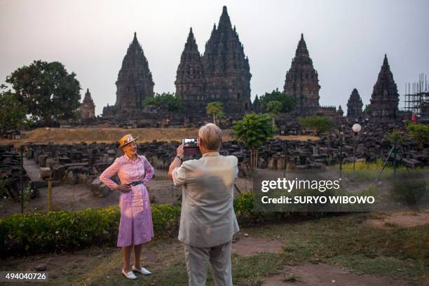 Danish Queen Margrethe II poses as Prince Consort Henrik takes a photograph at the Prambanan temple during their visit to Yogyakarta on October 24,...
