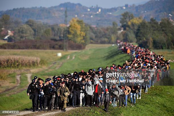 Migrants are escorted through fields by police and the army as they are walked from the village of Rigonce to Brezice refugee camp on October 24,...