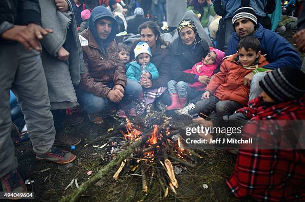 Migrants attempt to keep warm next to a fire as they are held back by the police near the village of Rigonce, before being walked to Brezice refugee...
