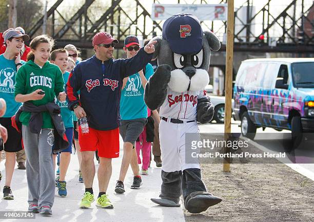 Portland Sea Dogs' mascot, Slugger, is escorted back to Hadlock Field with help from Justin LeBlanc of South Portland, center, and friends after...