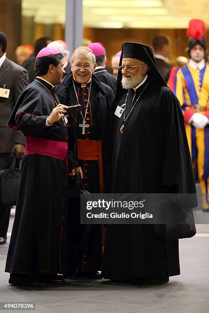 Cardinal Walter Kasper and Patriarch Gregory III Laham take a selfie with a bishop as they leave the closing session of the Synod on the themes of...