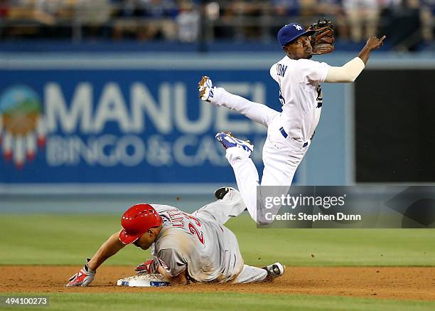 Second baseman Dee Gordon of the Los Angeles Dodgers watches his throw to first as he goes over baserunner Donald Lutz of the Cincinnati Reds in the...