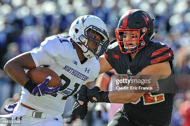 Running back Justin Jackson of the Northwestern Wildcats tries to break the grip of linebacker Josh Banderas of the Nebraska Cornhuskers during their...