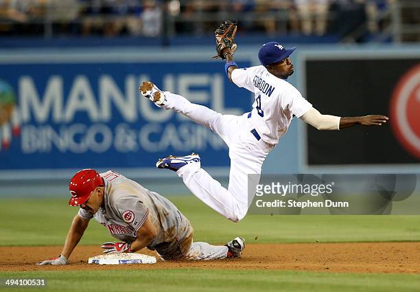 Second baseman Dee Gordon of the Los Angeles Dodgers watches his throw to first as he goes over baserunner Donald Lutz of the Cincinnati Reds in the...