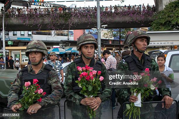 Thai soldiers hold roses that they received from coup supporters during an anti-coup demonstration at the Victory Monument in Bangkok, Thailand on...