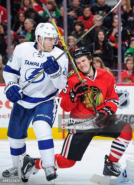 Matt Carle of the Tampa Bay Lightning and Andrew Shaw of the Chicago Blackhawks get physical in the third period of the NHL game at the United Center...