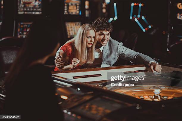 excited couple  gambling at electronic roulette in casino - roulotte stock pictures, royalty-free photos & images