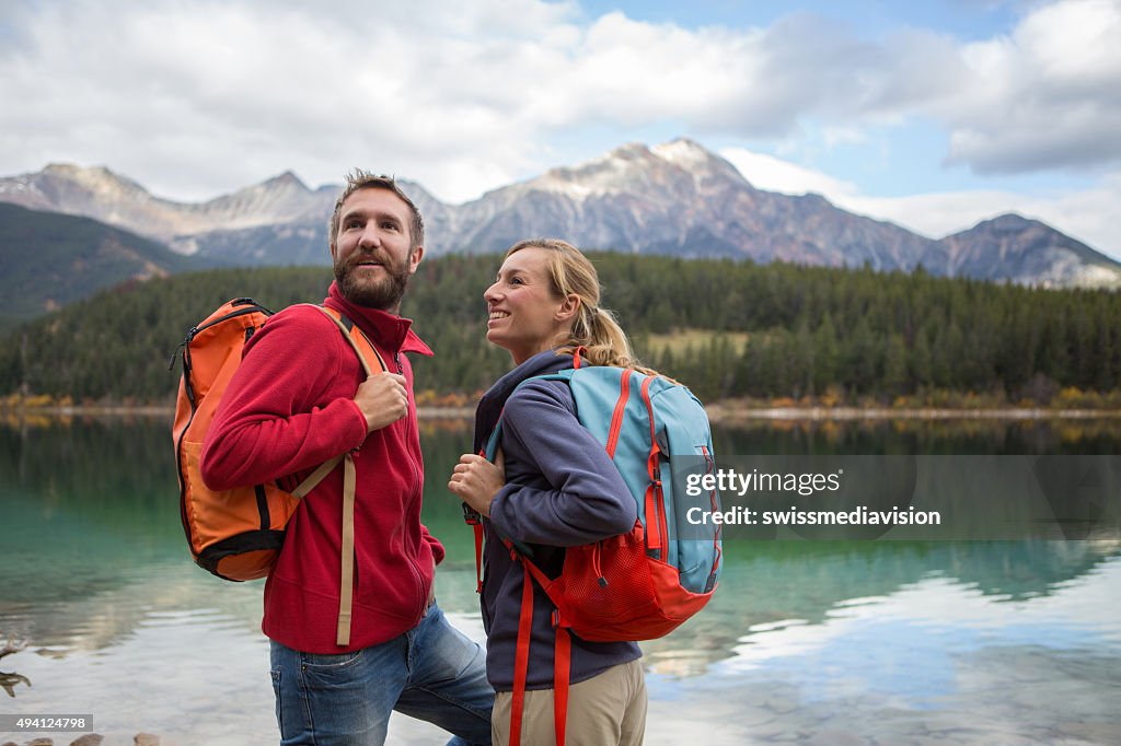 Young cheerful couple hiking by the lake in Autumn