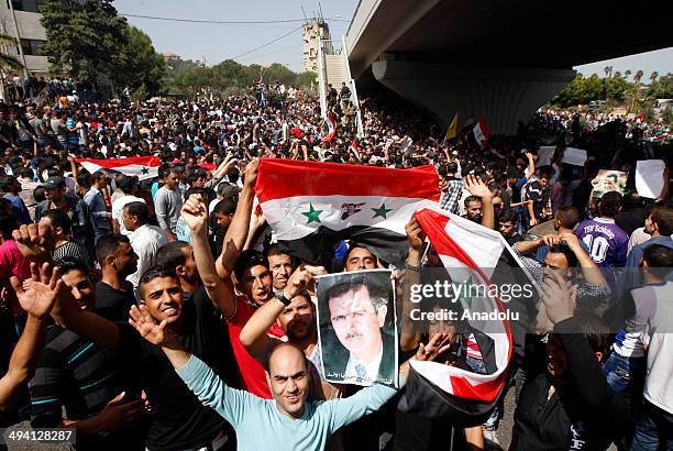 Syrians living in Lebanon, hold the posters of President Bashar al-Assad and national flags as they arrive at the Syrian Embassy in Beirut on May 28,...