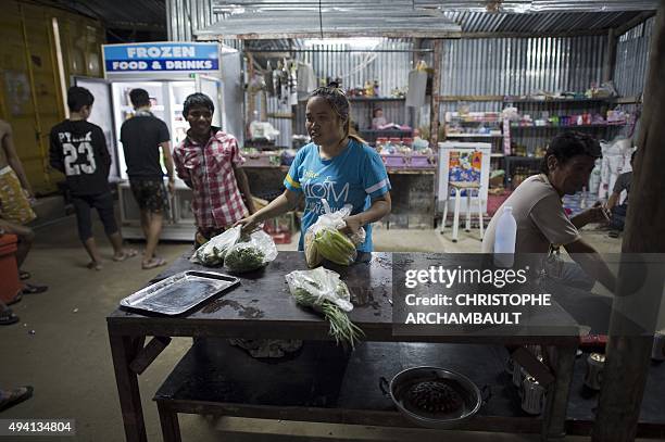 Thailand-economy-migrants-society-construction, FEATURE by Reuben Easey This picture taken on October 1, 2015 shows a woman storing vegetables before...