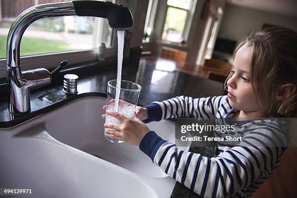 girl getting water from kitchen sink - girl filling water glass stock pictures, royalty-free photos & images