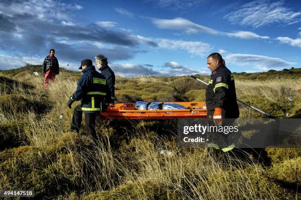 Firemen carry the body of a child after refugees and migrants arrived by boats on the Greek island of Lesbos after crossing the Aegean sea from...