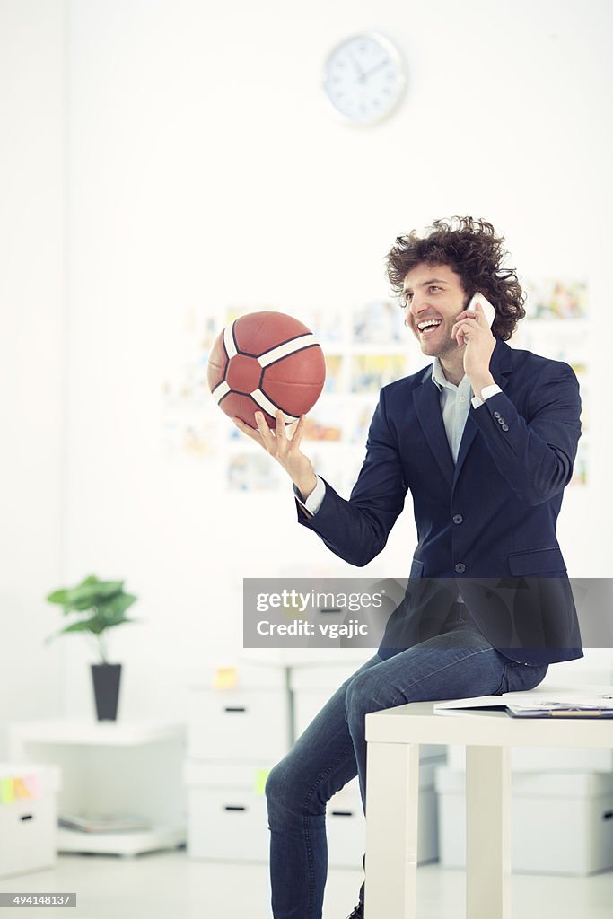 Young Businessman Holding Basketball Ball and talking on the phone.