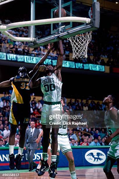 Robert Parish of the Boston Celtics shoots a layup against Dale Davis of the Indiana Pacers during a game played at the Boston Garden in Boston,...