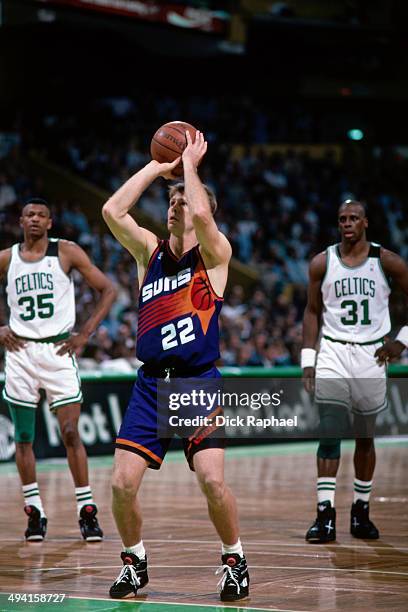 Danny Ainge of the Phoenix Suns attempts a free throw as Reggie Lewis and Xavier McDaniel of the Boston Celtics look on during a game played at the...