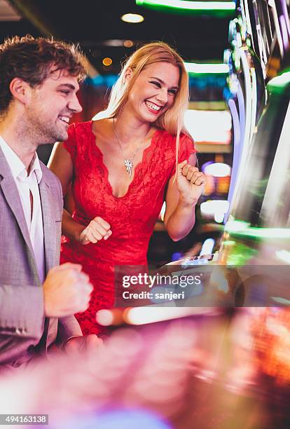 young couple playing slot machines at the casino - casino elegance stock pictures, royalty-free photos & images