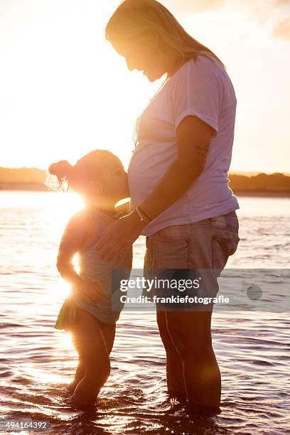 rapariga beijar a barriga da mãe grávida - little kids belly imagens e fotografias de stock