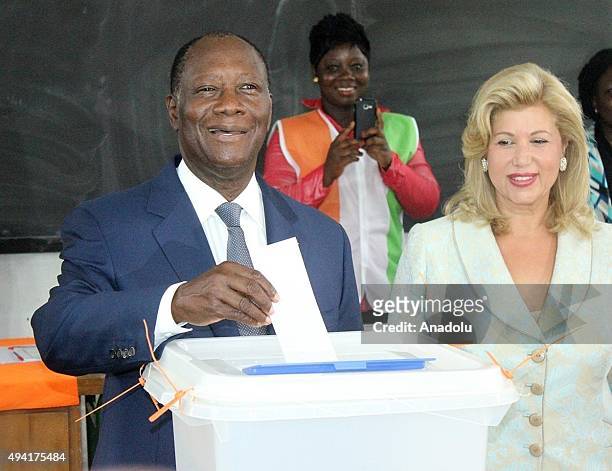 President of Ivory Coast Alassane Ouattara casts his vote while his wife Dominique Folloroux-Ouattara looks on in Saint Mary High School during the...