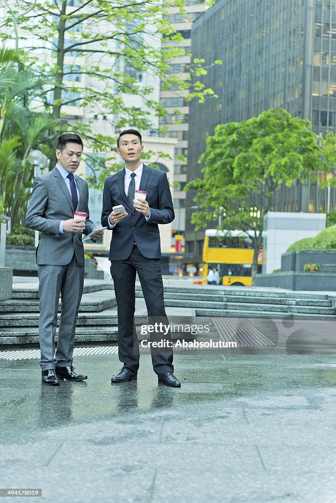 Dois homens de negócios com dispositivo móvel, na Ásia, Hong Kong,