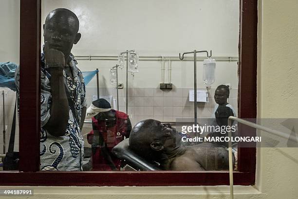 Relatives look on as a wounded man rests in the ward of the "Hopital Communautaire" in Bangui on May 28, 2014. At least 10 people were killed and...