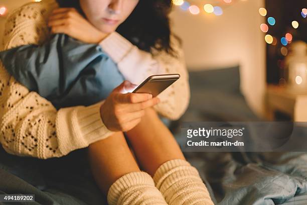 menina na cama, usando telefone - assédio imagens e fotografias de stock