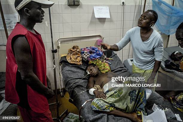 Relatives reacts as they stand over a wounded woman receiving medical care resting in the ward in the ward of the "Hopital Communautaire" in Bangui...