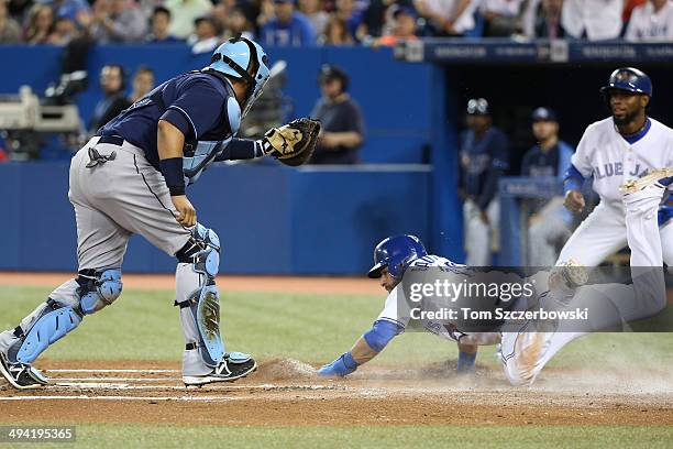 Jose Bautista of the Toronto Blue Jays slides safely into home plate to score a run in the first inning during MLB game action as Jose Molina of the...