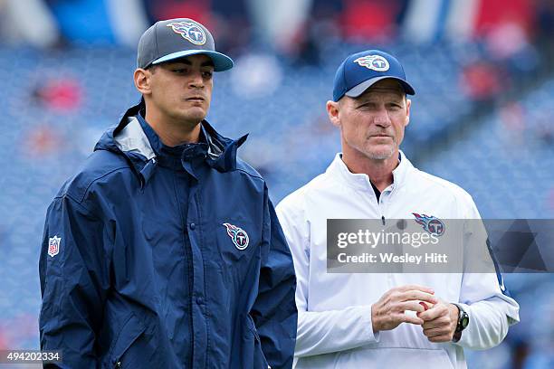 Head Coach Ken Whisenhunt and a injured Marcus Mariota of the Tennessee Titans watch the team warm up before a game against the Atlanta Falcons at...