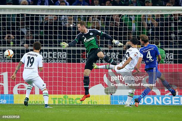 Lars Stindl of Moenchengladbach scores the first goal after a second try of penalty against Ralf Faehrmann of Schalke and Benedikt Hoewedes of...