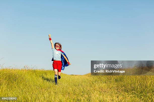 young girl dressed as superhero running in grass - superhero kid stockfoto's en -beelden