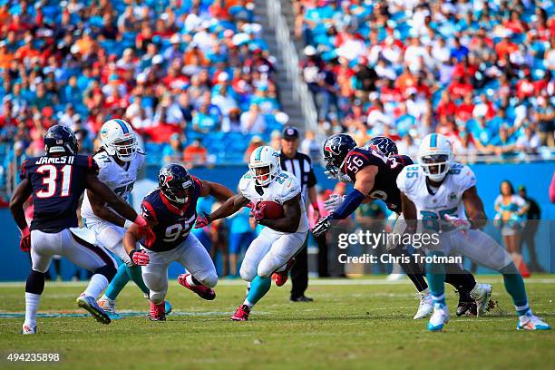 Jonas Gray of the Miami Dolphins rushes with the ball as Christian Covington of the Houston Texans looks on at Sun Life Stadium on October 25, 2015...