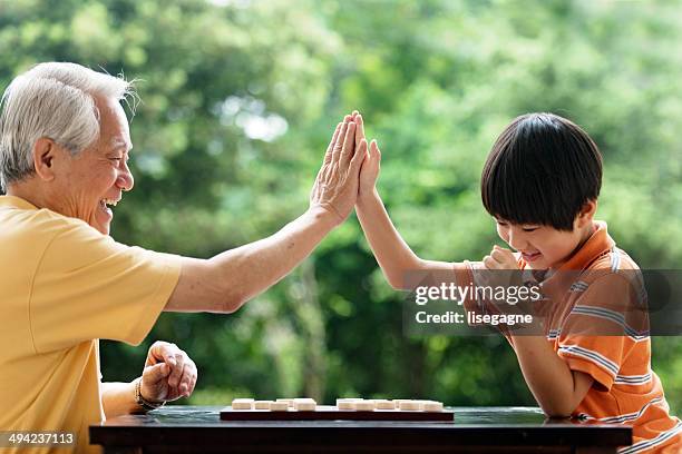 großvater und enkel spielt schach xiangqi (chinesisch) - 2014 asian games stock-fotos und bilder