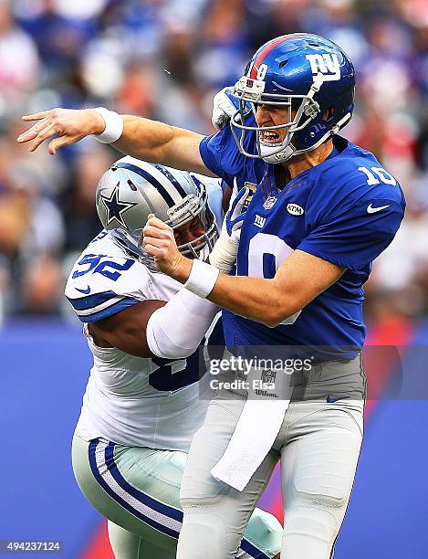 Eli Manning of the New York Giants is hit as he throws by Jeremy Mincey of the Dallas Cowboys during the first quarter at MetLife Stadium on October...