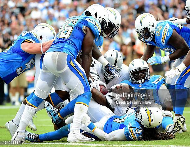 Marcel Reece of the Oakland Raiders loses his helmet as he hangs on to the ball against the San Diego Chargers defense at Qualcomm Stadium on October...