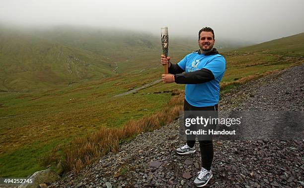 In this handout image provided by Glasgow 2014 Ltd, Baton bearer and Paralympic Gold Medalist Aled Davies, holds the Queen's Baton at the halfway...