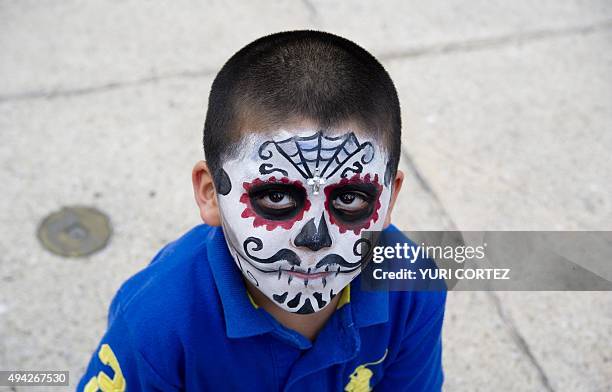 Boy painted as "Catrin" poses for pictures at the Angel of Independence square before taking part in the Procession of the Catrinas along Reforma...